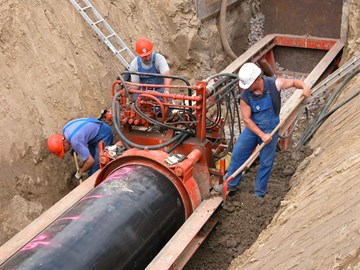Drei Mitarbeiter arbeiten in einer Baugrube an Rohrleitungen Drei Mitarbeiter arbeiten in einer Baugrube an Rohrleitungen