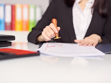 Hände einer Frau mit Siegelstempel über einer Urkunde Hände einer Frau mit Siegelstempel über einer Urkunde