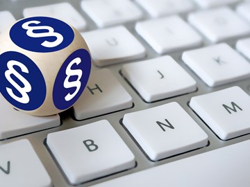 Ein Würfel, mit Paragrafenzeichen auf jeder Fläche, liegt auf einer Tastatur Ein Würfel, mit Paragrafenzeichen auf jeder Fläche, liegt auf einer Tastatur